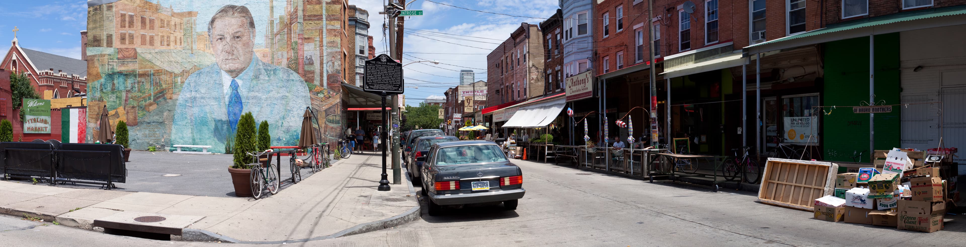 A panoramic view of the historic Italian Market — the awning-covered curb stalls and storefronts along South 9th Street.