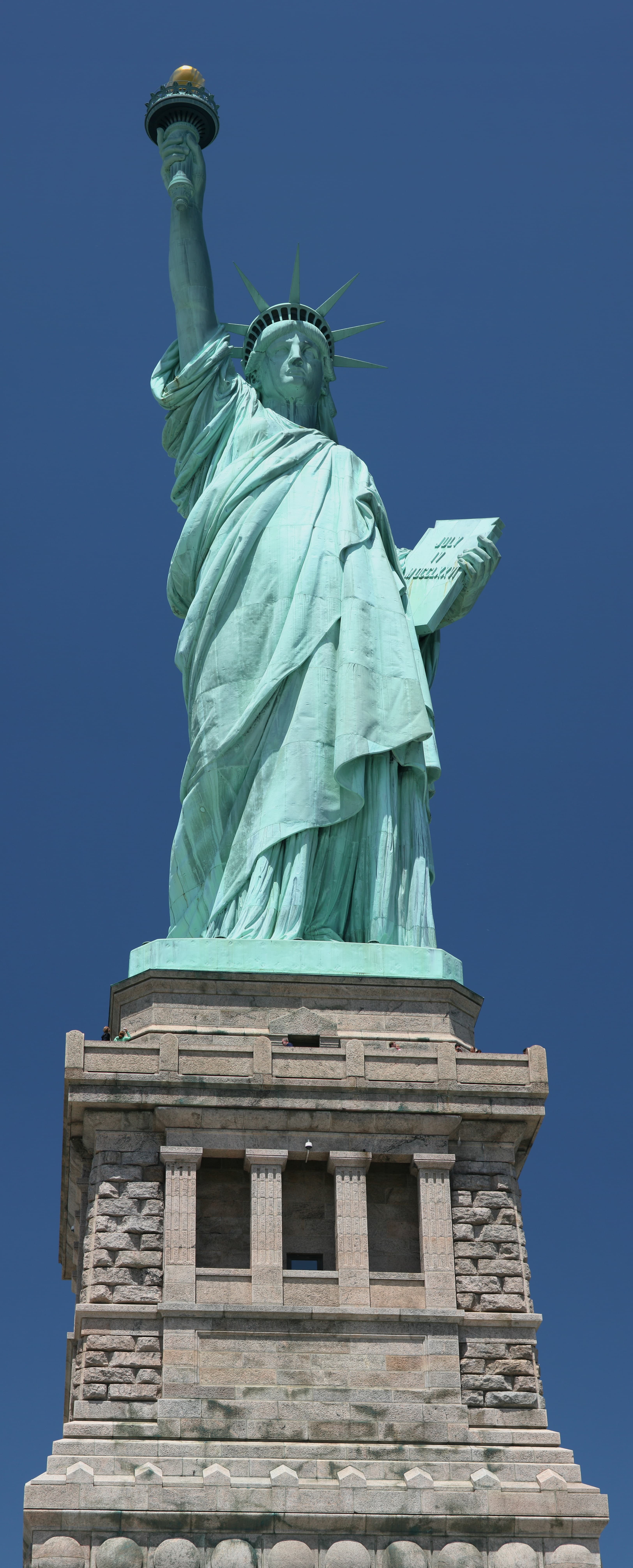 The Statue of Liberty seen head-on from the island grounds, copper figure on granite pedestal above the walls of old Fort Wood
