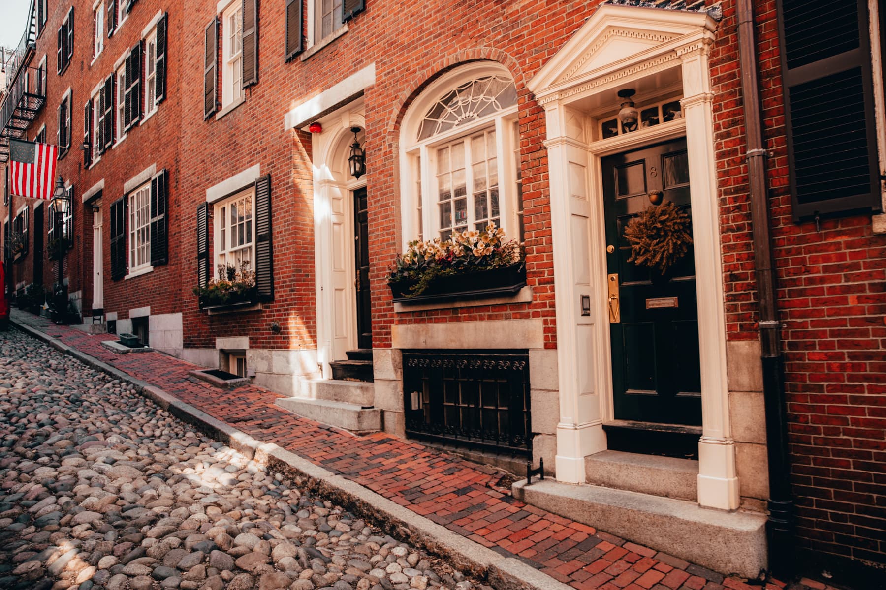 Hero photo: Shawn M. Kent, CC BY-SA 4.0, via Wikimedia Commons. Acorn Street, the 1820s river-cobble lane of coachmen's houses on Beacon Hill's south slope.