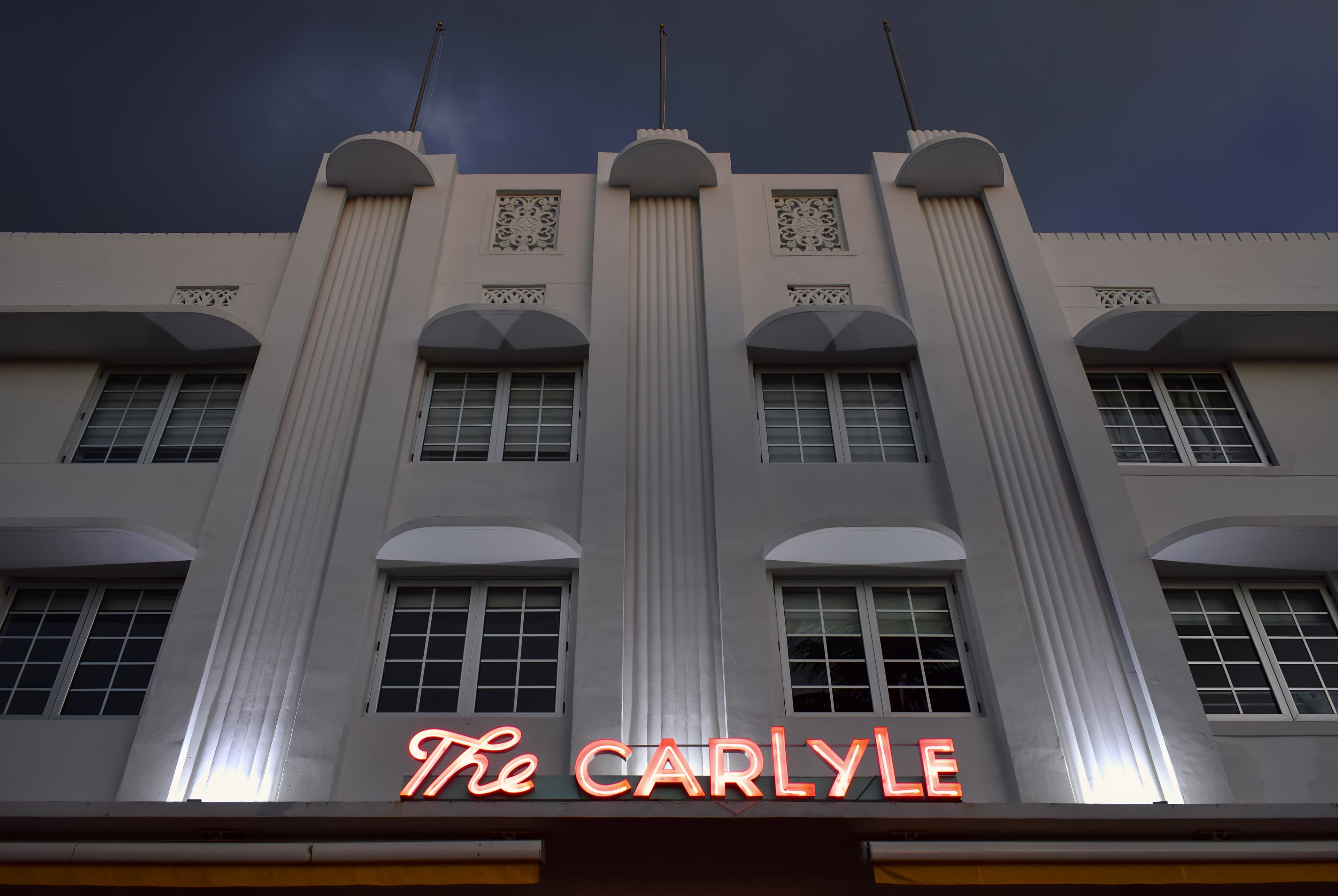 Neon signage glowing on the Carlyle Hotel at 1250 Ocean Drive, seen from the east looking up