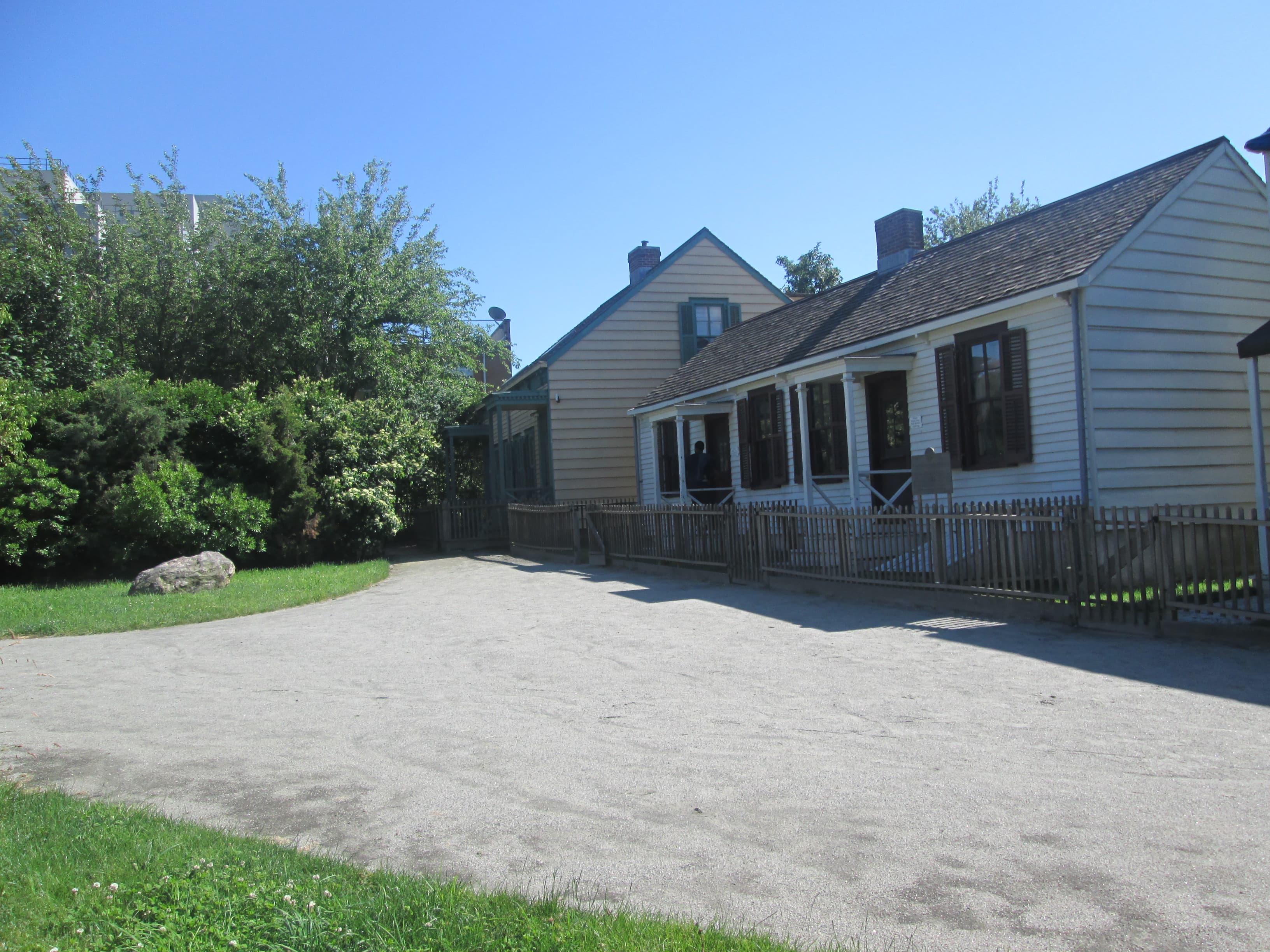 Historic clapboard houses with a picket fence along a gravel path at Weeksville