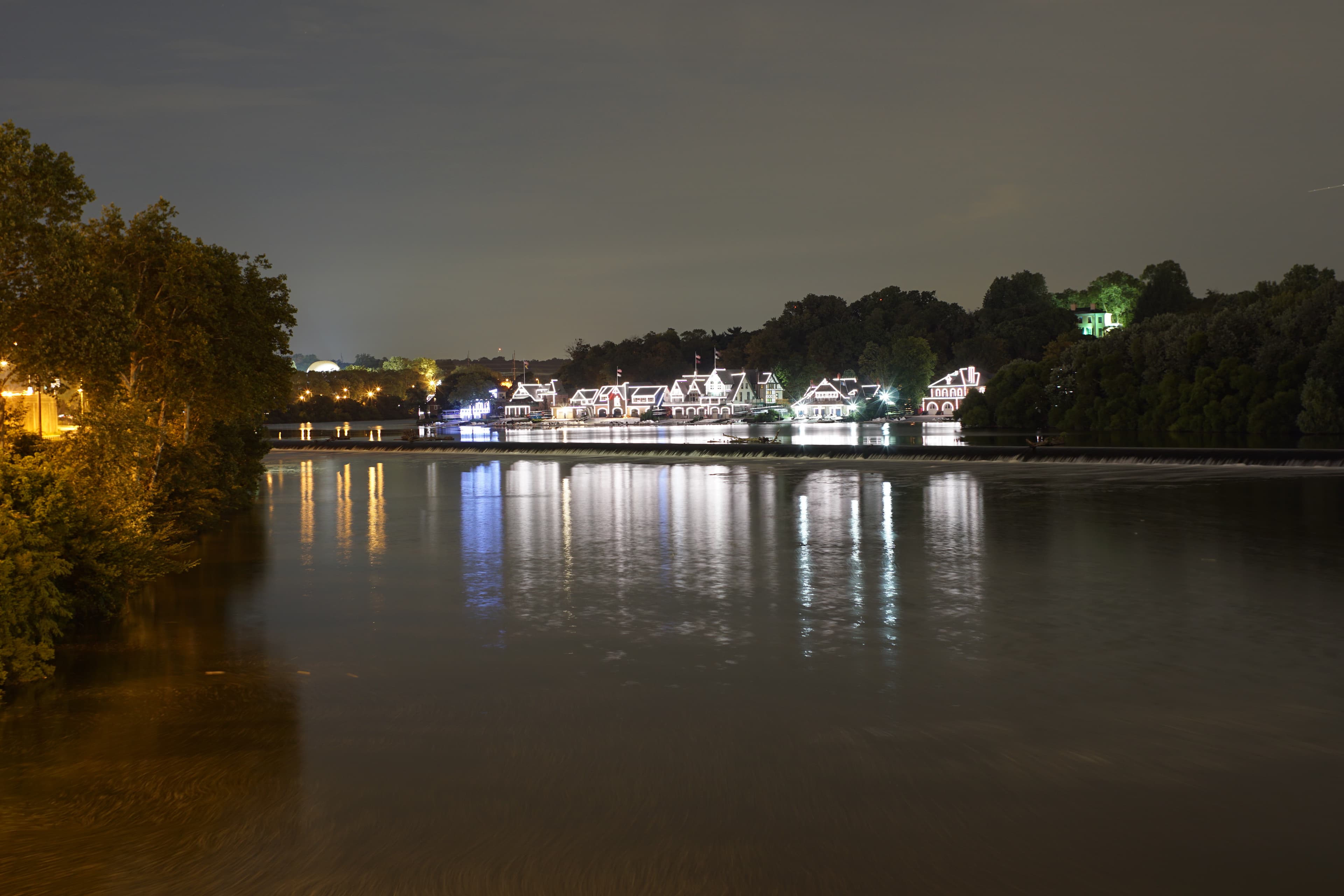 Boathouse Row in daylight, seen across the Schuylkill River — the full line of Victorian boathouses on the east bank.
