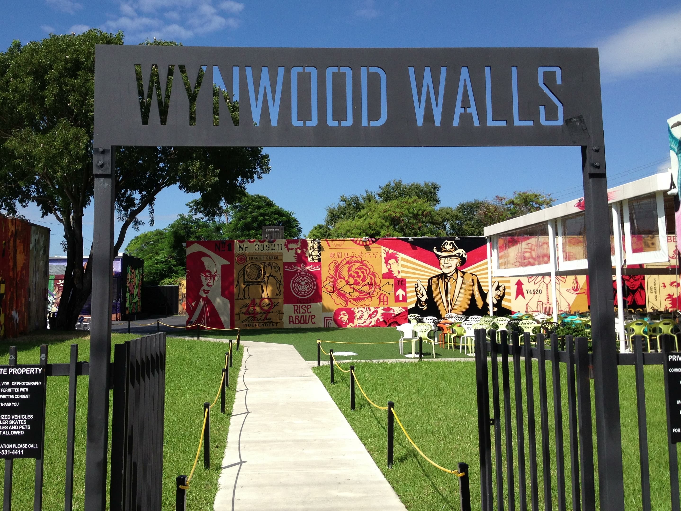 Photo: Phillip Pessar, CC BY 2.0, via Wikimedia Commons. Mural-covered warehouse walls at Wynwood Walls, photographed September 2013 — the outdoor museum's signature large-scale format.